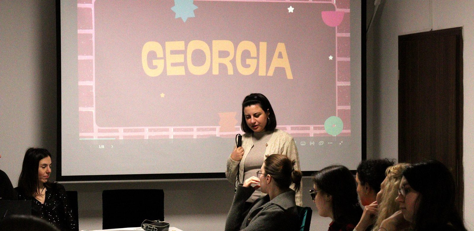 A Mariani team member presenting Georgia with a microphone, under the projected “Georgia” slide.