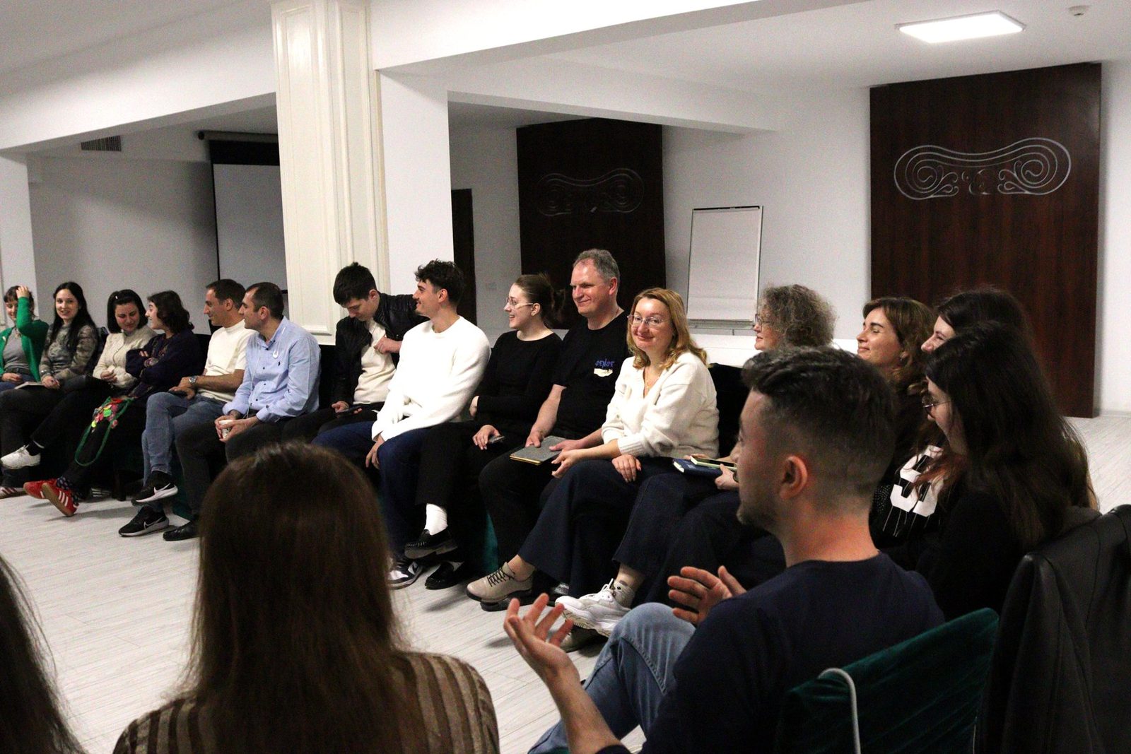 The whole group seated in a wide semicircle, listening during the country presentations.